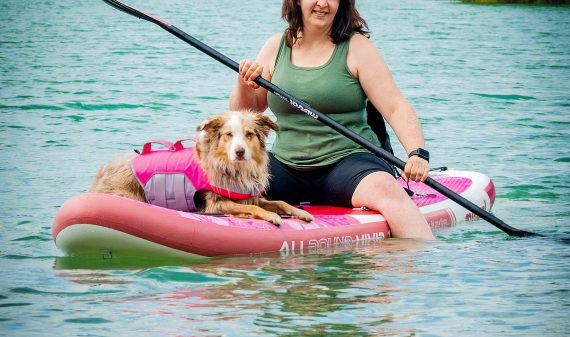 Human with a dog paddle boarding